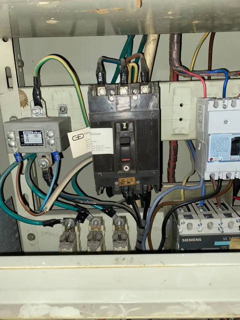 Ana şalter ve farklı renklerde kablolar bulunan elektrik panosu