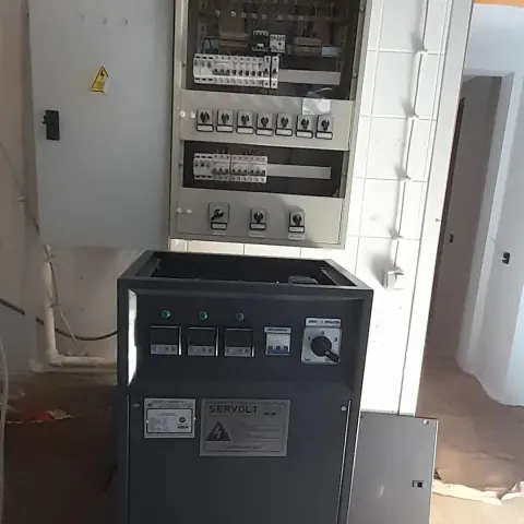 Duvar tipi elektrik panosu ve önünde voltaj regülatörü
