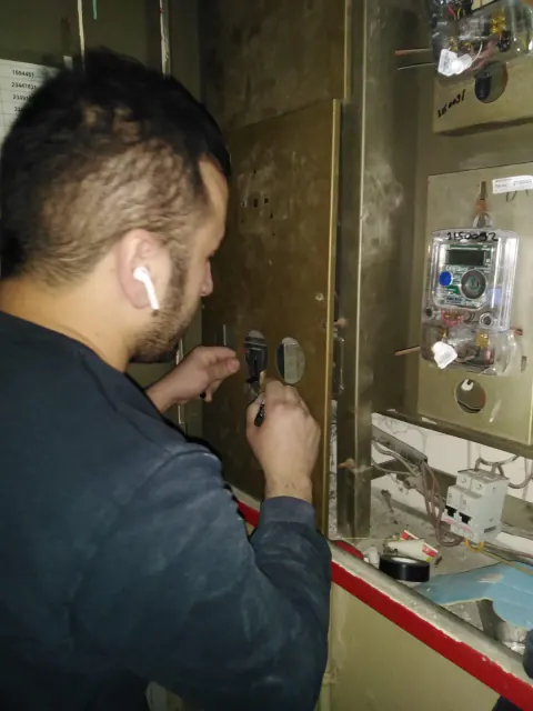 Elektrik sayaç panosunda el aletiyle çalışan teknisyen