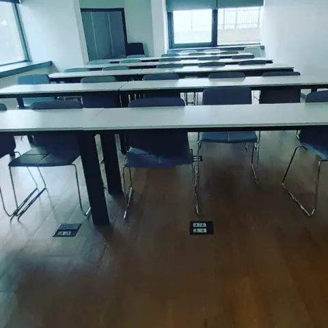 Eğitim veya toplantı salonunda masa aralarında bulunan zemin prizleri