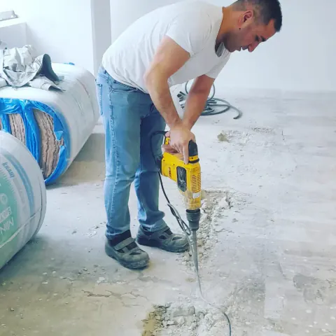 Elektrikli kırıcıyla zeminde kablo kanalı hazırlayan usta